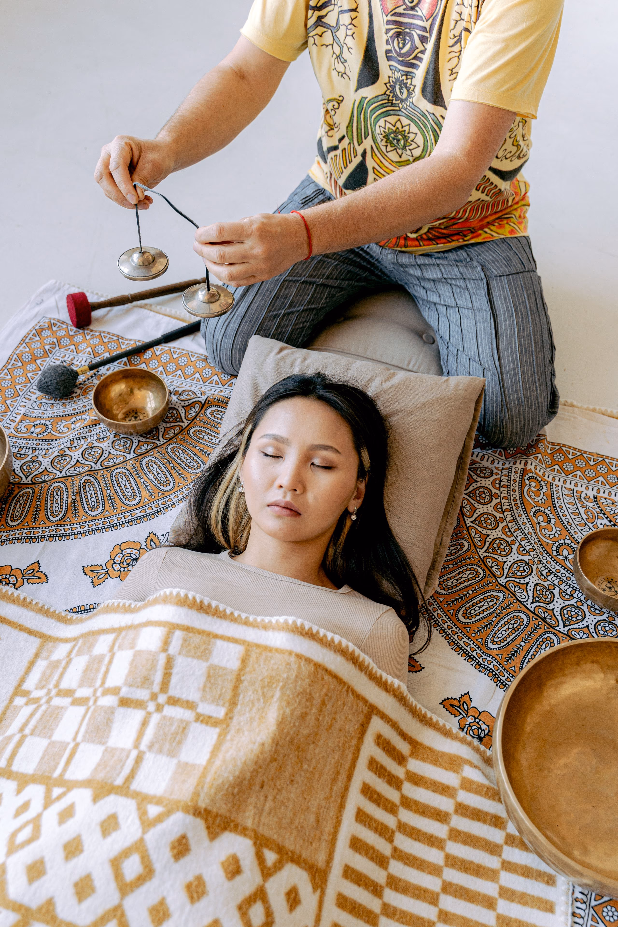 Someone resting under a gold and cream blanket with a cushion under their head.