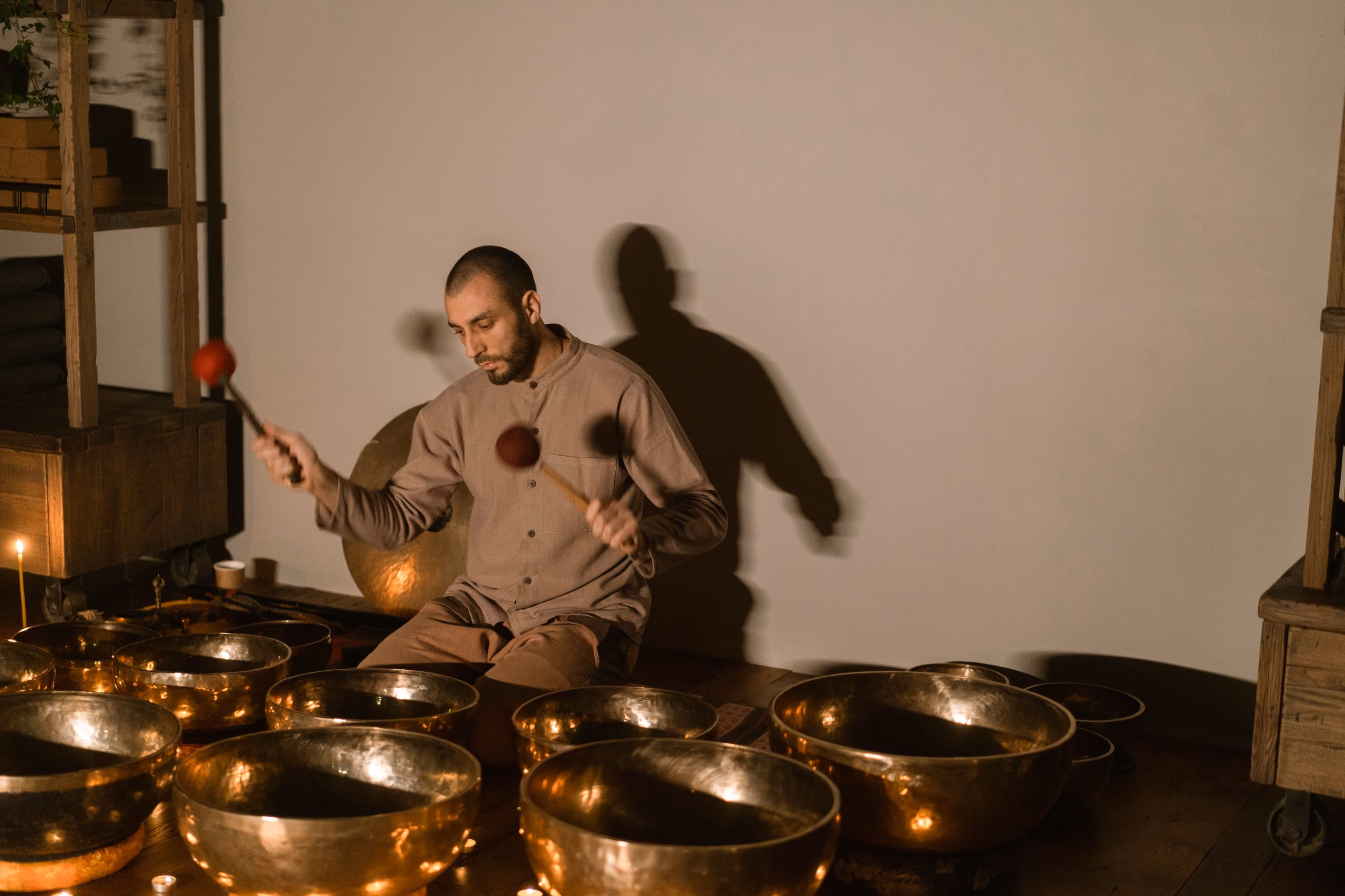 A row of frosted crystal singing bowls behind a line of lit tealights.