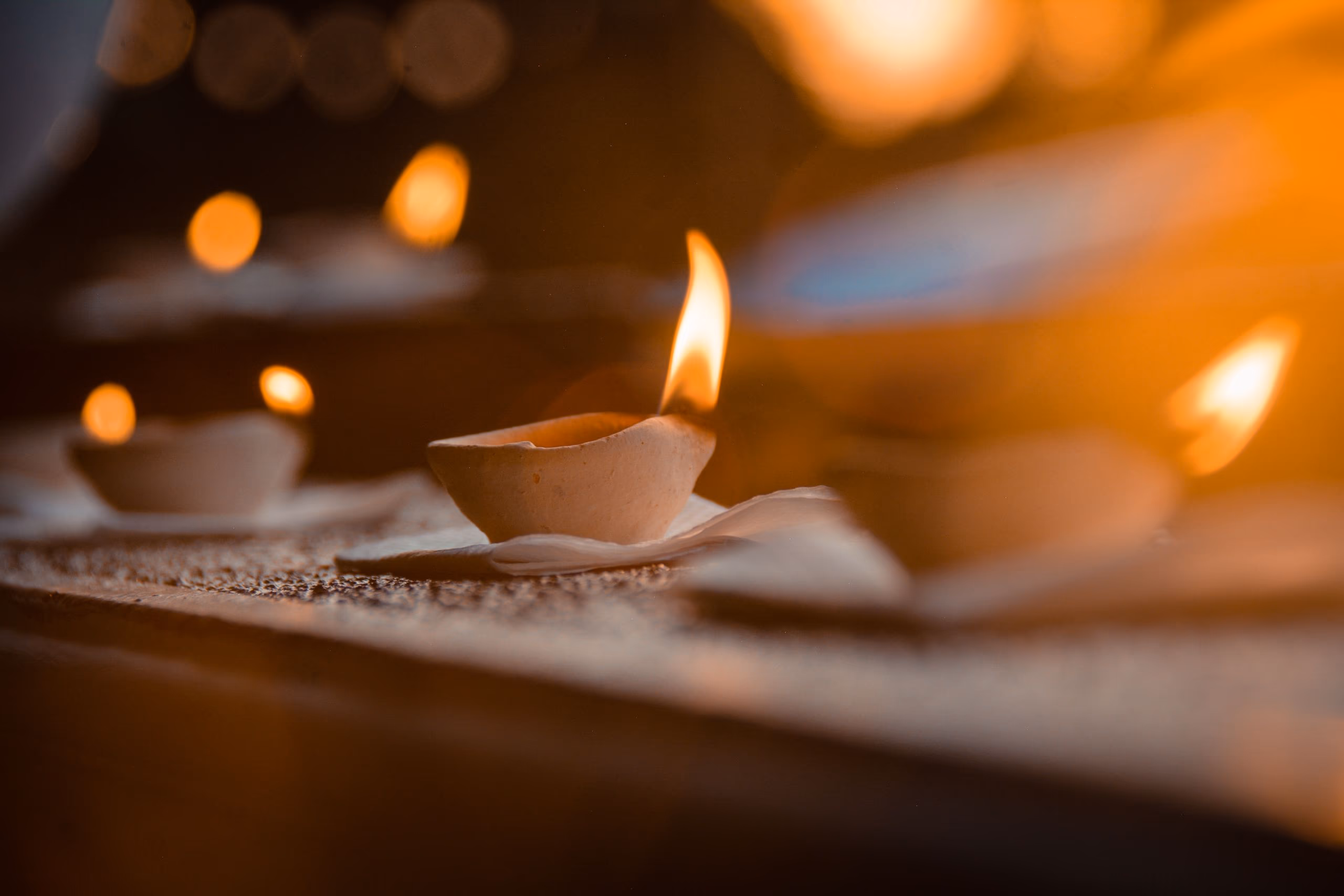A single small flame in focus, with warm amber light blurred behind it.
